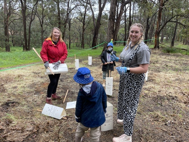 Two women and two children planting seedlings