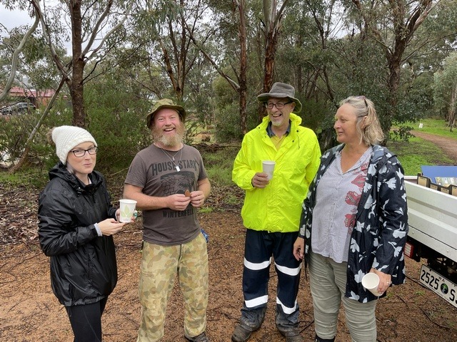 two men and two women standing in front of bush