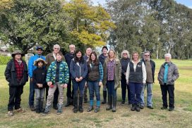 several men and woman posing for a photo in a bush setting