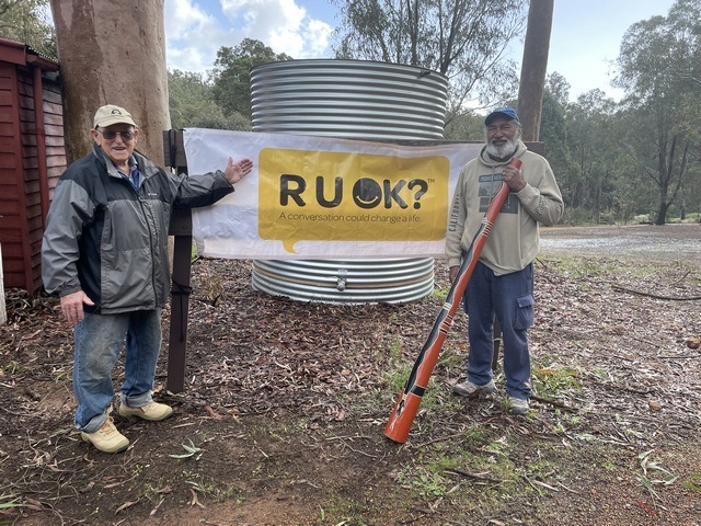 two men standing in front of an RUOK banner